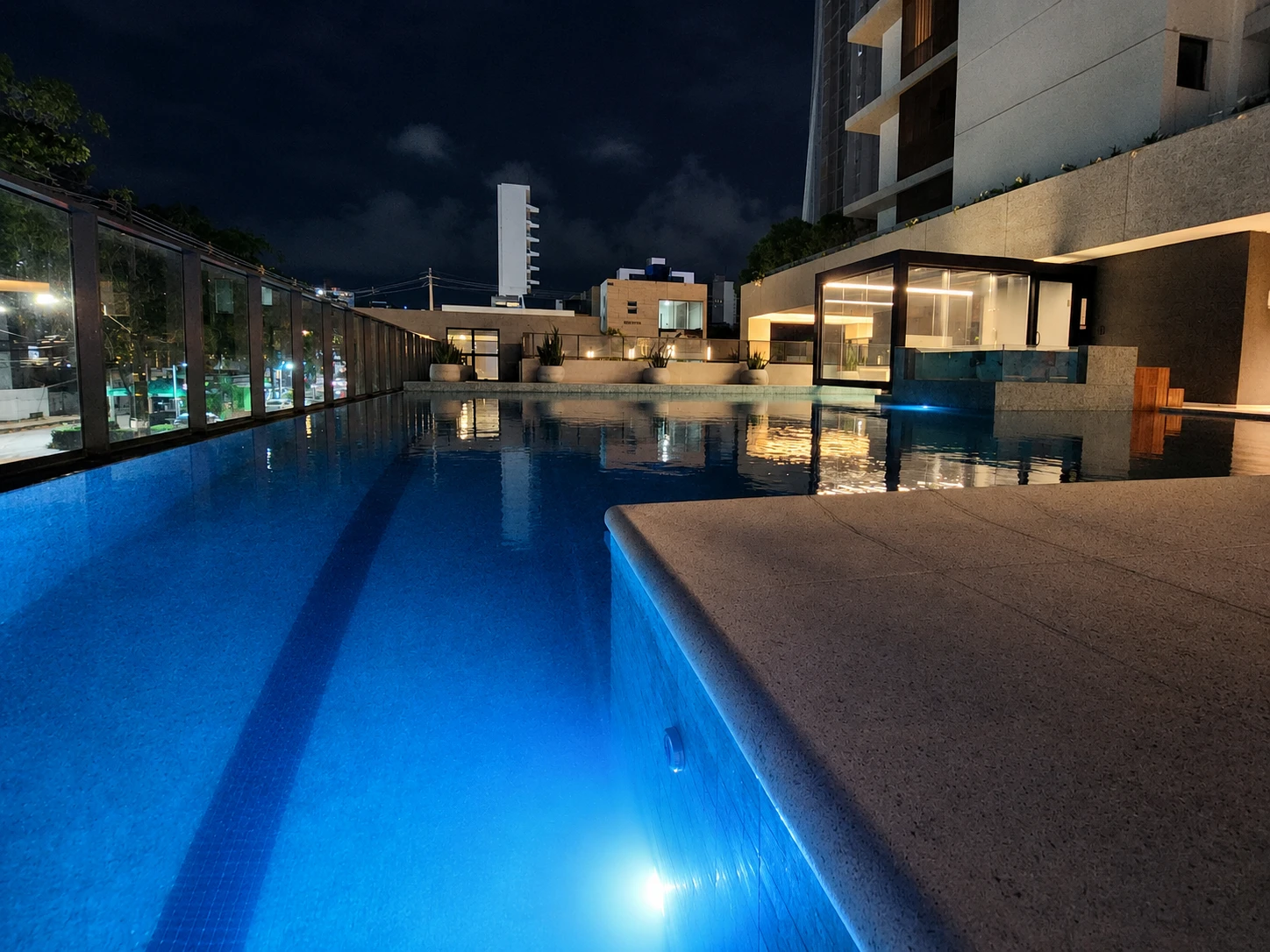 Piscina iluminada do Afonso 1095 com área de lazer e arquitetura do edifício