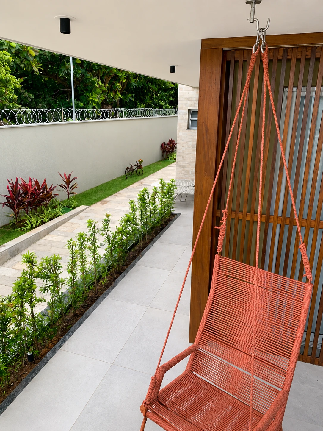 Área de descanso com cadeira suspensa e jardim no Marítimo Residence